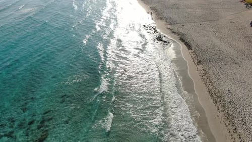 Drone Moves Along Sandy Beach and Turquoise Waves of Mediterranean Sea on Sunset. Aerial View of