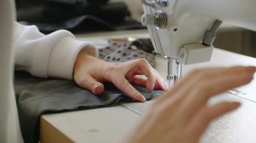 Hands Sewing Gray Fabric with Sewing Machine