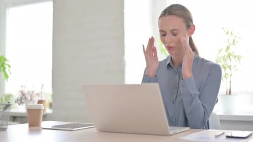 Woman Working at Laptop with Headache in Office