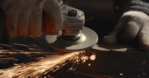 Locksmith Sands the Edges of a Metal Detail By Electric Grinder with a Lot of Sparks in Slow Motion