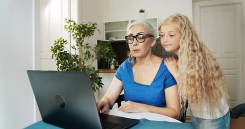 Girl Helping Grandmother Use Laptop at Home