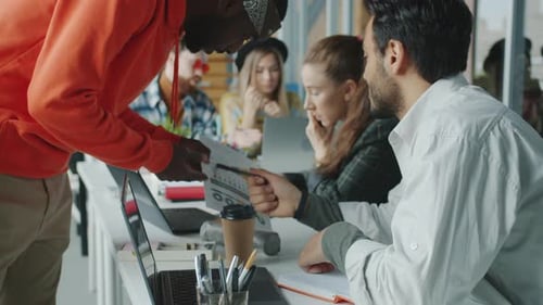 Equipe de negócios multirracial trabalhando no escritório falando usando computadores e discutindo o trabalho no celular