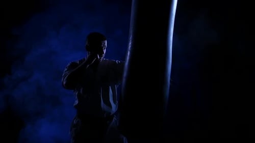Karate Man Punching Heavy Bag in Dark Room