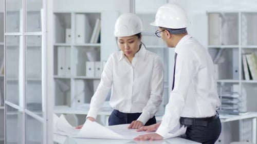 Multiethnic Engineers in Hardhats Discussing Technical Drawings