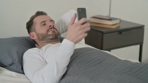 Man Lying in Bed Using Mobile Phone