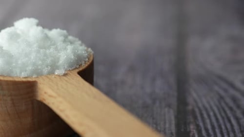 Pile of White Crystals in Wooden Measuring Spoon