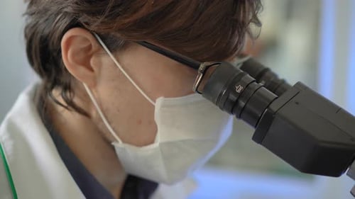 Medical Professional Works with Microscope in Bright Lab