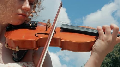 Woman Plays Violin Outdoors on Sunny Day