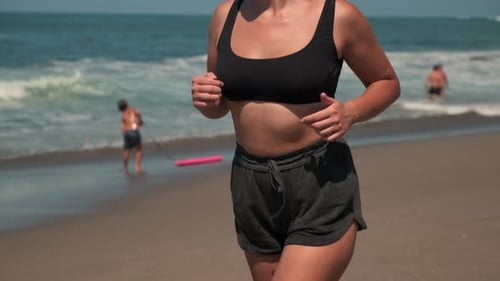Unerkennbare Frau joggt am Sandstrand eines Meeres