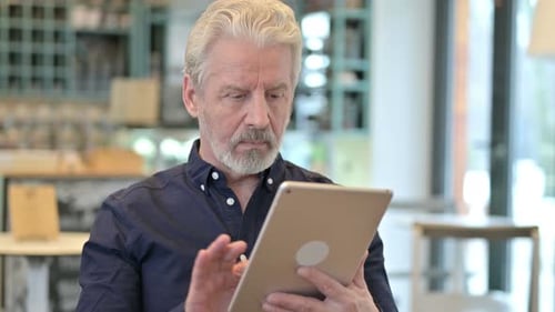 Mature Man Using Tablet Indoors