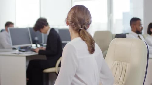 Woman Stretching at Desk in Bright Office