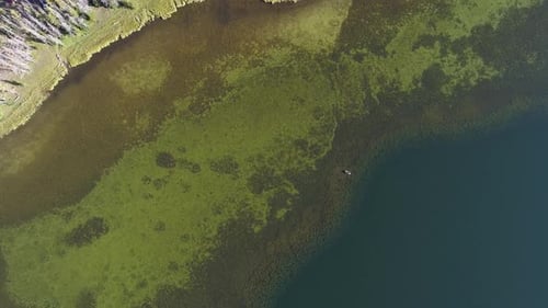 Aerial view over color green lake flying towards the surface