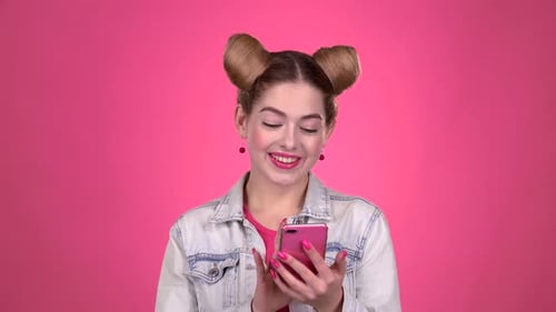 Adolescente pulsa una foto en un teléfono inteligente. Fondo rosa