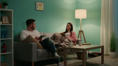 Couple Relaxing on Couch at Home at Night