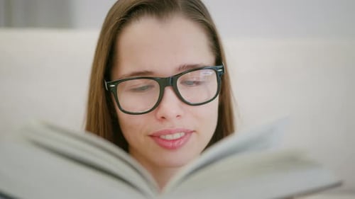 Close up of student spending time in library, carefully reading book. Student lifestyle, education.