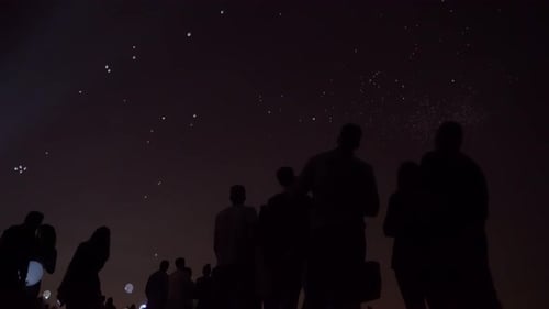 Silhouettes Watch Lanterns Float Into Night Sky