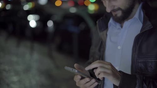 Man Using Smartphone in Urban Setting at Night