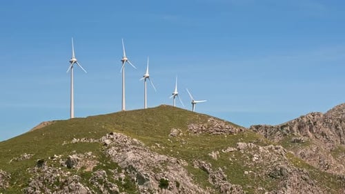 Diagonale Nahaufnahme eines Windturbinenparks in Hügellandschaft an einem sonnigen Tag