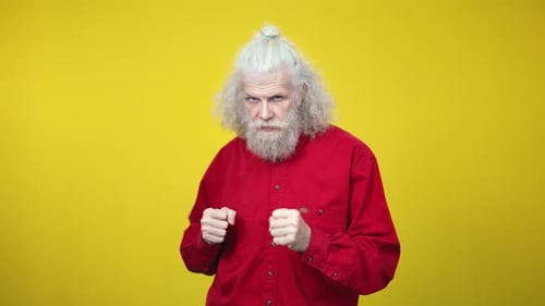 Angry Senior Man Boxing Against Yellow Background