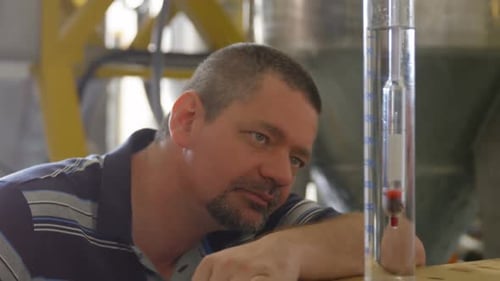 Travailleur examinant le gin dans un cylindre de mesure