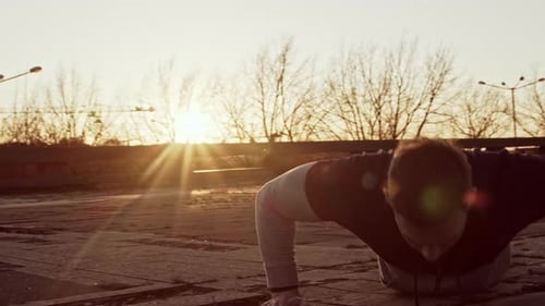 Man Doing Push-ups at Sunrise in Urban Setting