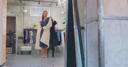 Garota elegante sai do provador de uma loja de roupas com um vestido longo e se admira em