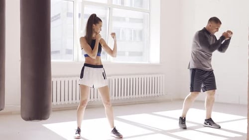 An Experienced Trainer Puts the Technique of Blows To a Young Girl in the Boxing Hall