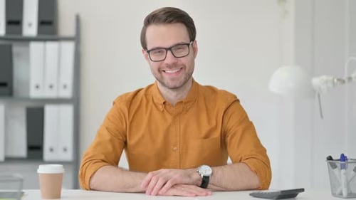 Man Smiling at Desk in Office Environment