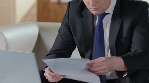 Adult Reviews Data at Work on a Laptop