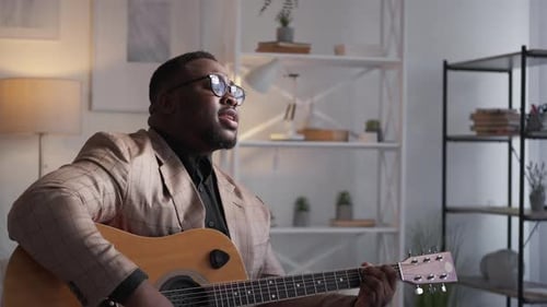 Stylish Man Plays Guitar and Sings in Living Room
