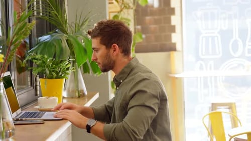 Hübscher Mann benutzt Laptop am Tisch 4k