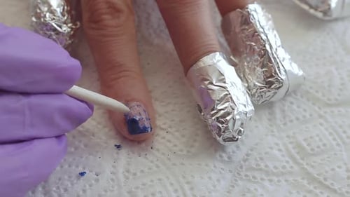 Nahaufnahme Frau entfernt altes Gel von den Nägeln mit orangefarbenem Stift. Frau bekommt Nagelmaniküre.