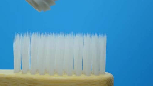 Weiße Zahnpasta kommt aus einer Tube auf einer Holzbürste