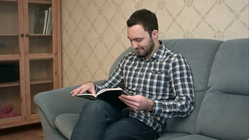 Man Reading Book on Couch at Home