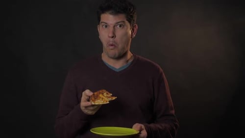 Man Eating Delicious Pizza Slice in Dark Room