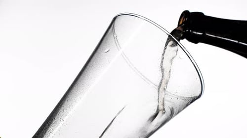 El proceso de verter cerveza en el vaso. Fondo naranja brillante