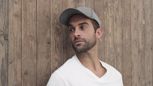 Handsome Man Poses Against Wooden Wall in Gray Cap