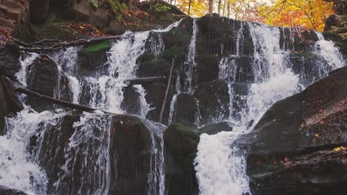 Wasserfall fällt Berghang im Herbstwald hinunter