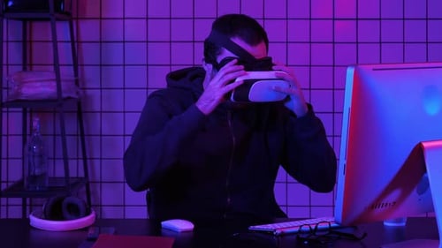 Man Uses VR Headset at Computer at Night