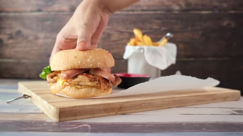 Hand Holding Beef Burger on Table Close Up