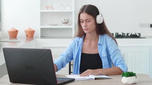 Woman Studying with Laptop and Notebook at Home