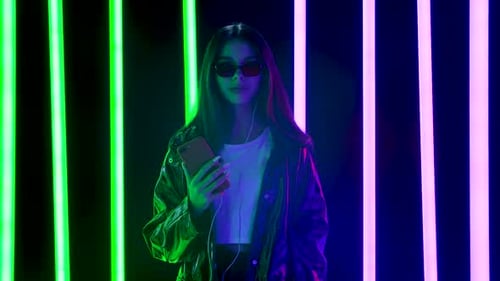 Stylish Woman Using Phone Against Neon Lights