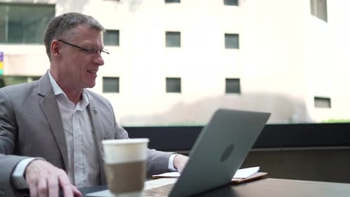 Smiling Man Working at Laptop in City