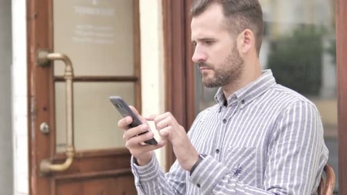 Man Using Cell Phone Outdoors in Urban Setting