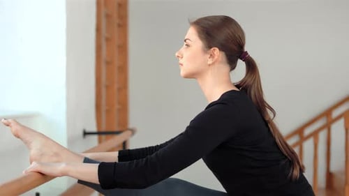 Young Sportive Woman Stretching Legs in a Gym