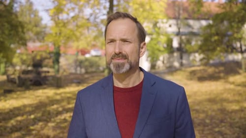 A Middleaged Handsome Caucasian Man Walks and Looks Around in a Park in Fall Front Closeup