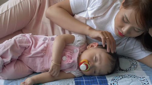 Mother Looks at Sleeping Infant on Bed