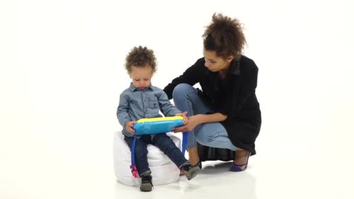 Afroamerikanische Mutter gibt ihrem Baby ein interessantes Spielzeug, weißer Hintergrund, Zeitlupe