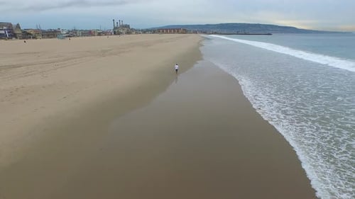 Luftaufnahme eines jungen Mannes, der am Strand rennt.