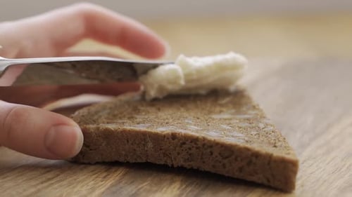 Cream Cheese Spreads Onto Slice of Rye Bread